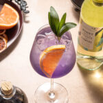 Magic Potion Wine Spritz, a delightful concoction featuring Sunny With a Chance of Flowers Sauvignon Blanc, Butterfly Pea Flower Syrup, grapefruit juice, and a touch of sparkling water.